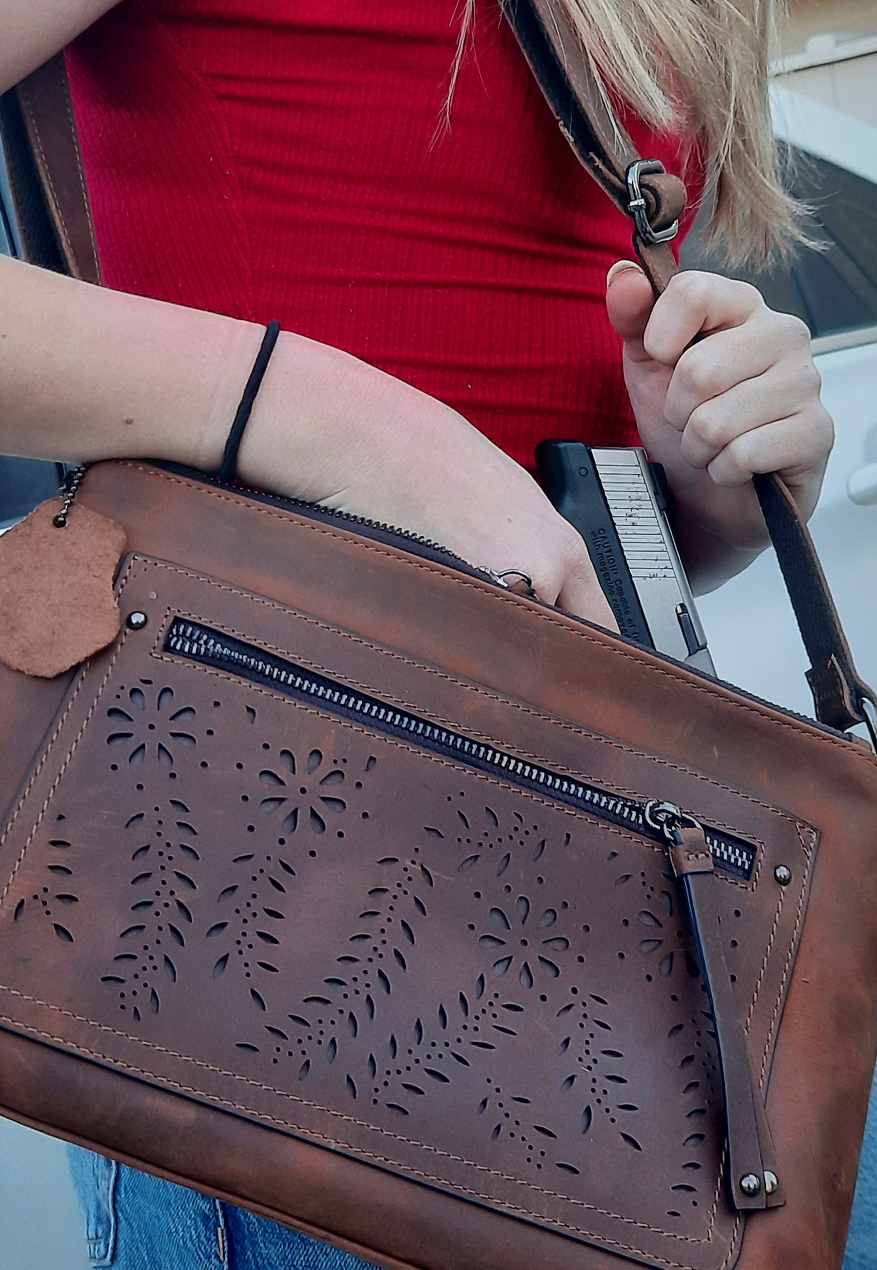 Gun compartment on leather conceal carry purse being demonstrated